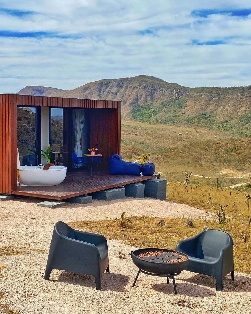 Deck com ofurô, firepit e poltronas diante das montanhas