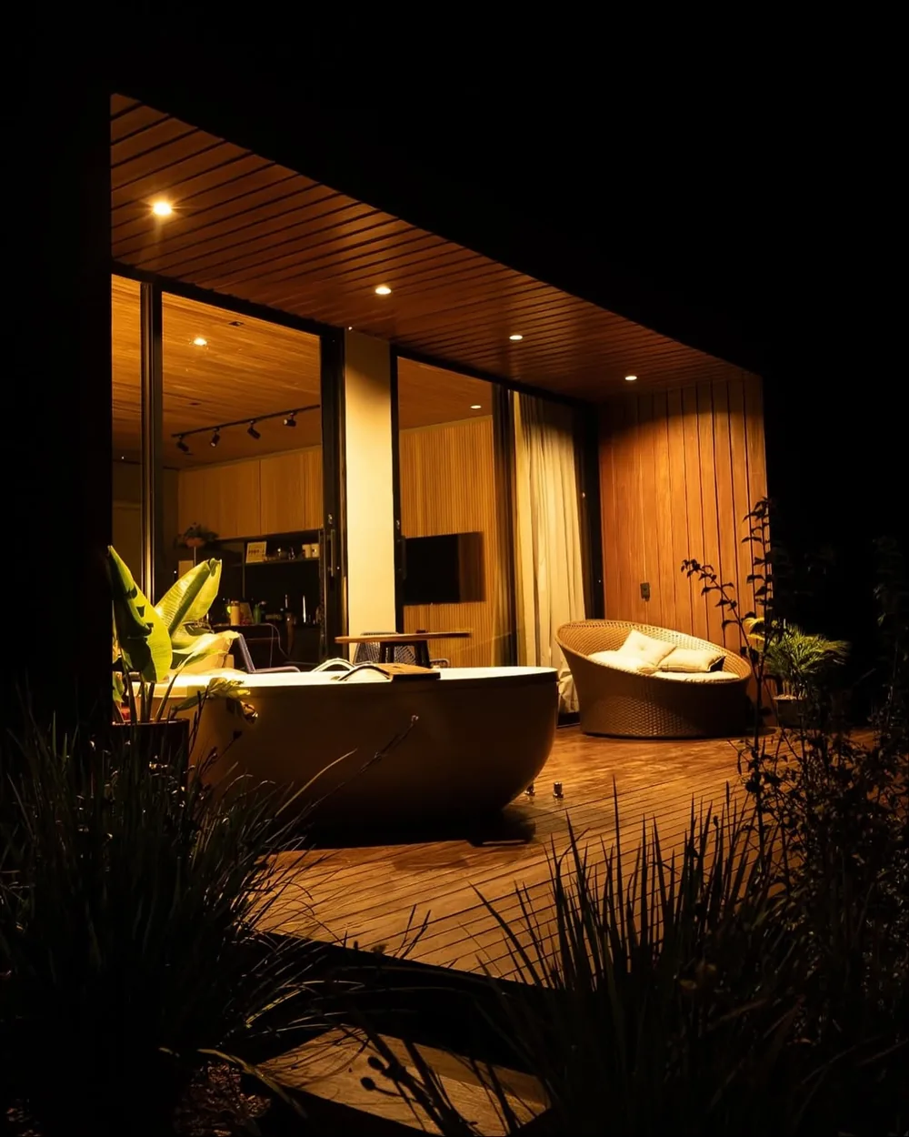 Cabana iluminada ao entardecer, com o ofurô no deck