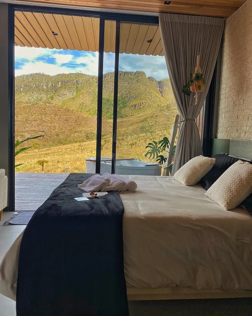 Suíte com cama king size aberta para a vista da serra