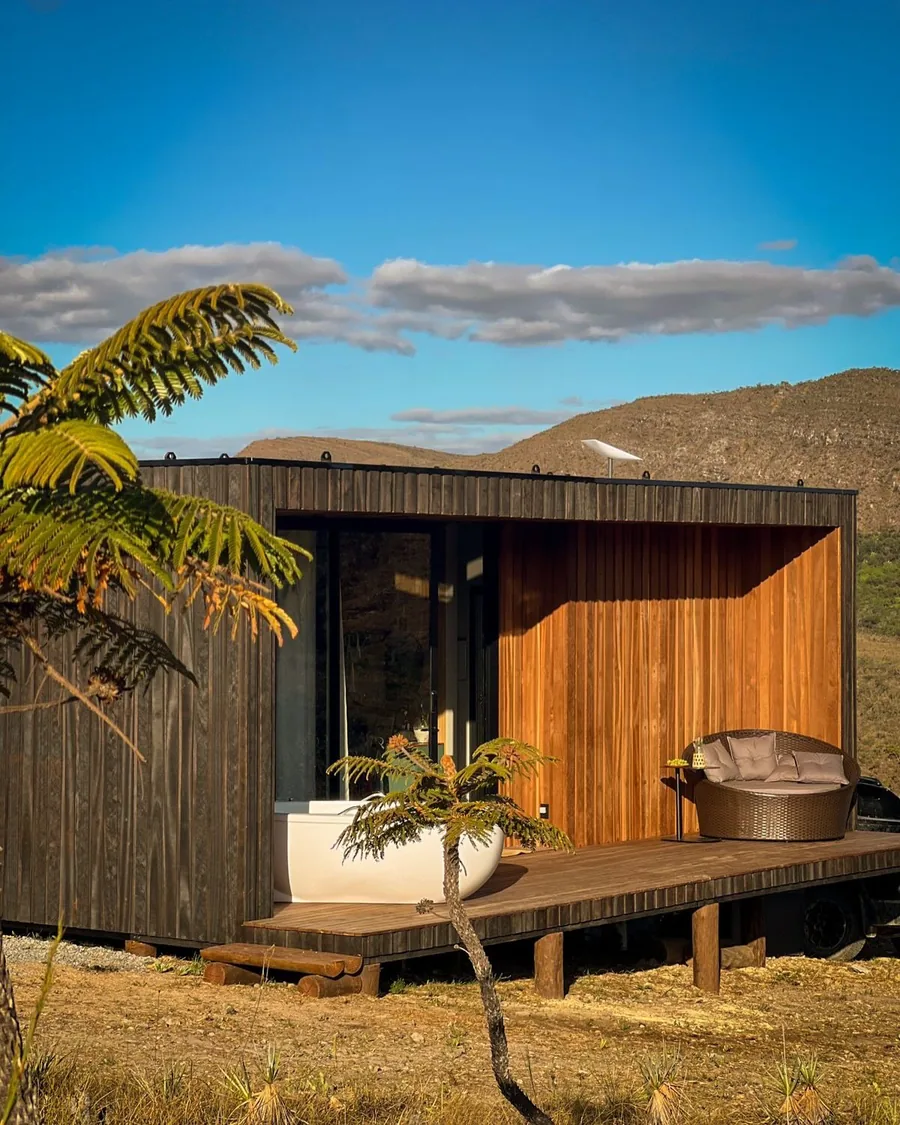 Cabana de madeira sozinha no alto do cerrado, com as serras ao fundo